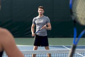 Tennisspieler im grauen T-Shirt und schwarzen Shorts auf einem Tennisplatz im Jumeirah at Saadiyat Island Resort