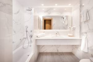 Innenansicht eines Badezimmers im Horizon Beach Resort mit weißen Marmorfliesen und einer Badewanne.