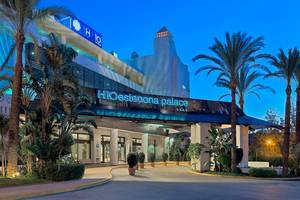 Eingang des H10 Estepona Palast Hotels mit Palmen und Beleuchtung