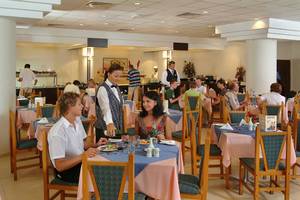 Ein Paar sitzt in einem Restaurant des Nestor Hotels und isst mit Kellnerin