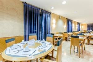 Frühstücksraum des Del Mar - Barcelona Hotels mit blauen Vorhängen und runden Tischen.