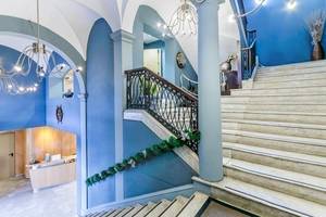 Der Eingangsbereich des Del Mar - Barcelona Hotels mit blauen Wänden, weißen Marmortreppen und schmiedeeisernem Geländer.