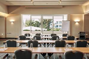Konferenzraum im Robinson Kyllini Beach Hotel mit Blick auf eine weiße Tafel und Palmen draußen.