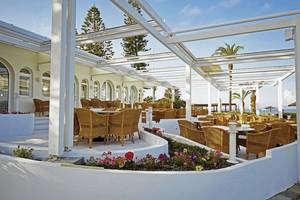 Außenterrasse des Robinson Kyllini Beach Hotels mit Tischen und Stühlen unter einem Pergoladach.