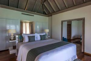 Schlafzimmer im Amaya Kuda Rah Hotel mit großem Bett, Lampen und Holzboden.