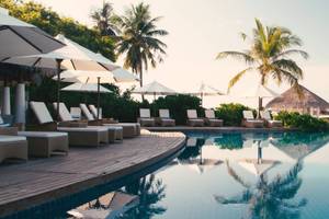 Pool-Loungebereich im Amaya Kuda Rah Hotel mit Sonnenliegen und Sonnenschirmen.