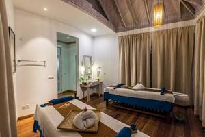 Massageraum im Hotel Amaya Kuda Rah mit zwei Massagetischen und einem Waschbecken.