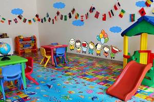 Kinderzimmer im Amaya Kuda Rah Hotel mit bunten Teppich, Tischen, Stühlen und Wandaufkleber.