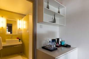 Innenansicht des Badezimmers im Amaya Kuda Rah Hotel mit gelben Wänden, weißem Waschbecken und Regal.