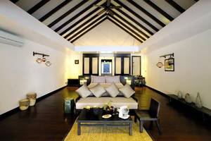Schlafzimmer im Atmosphere Kanifushi Maldives Hotel mit Bett, Couch, Tisch und Dekor.