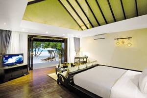 Innenansicht eines Hotelzimmers im Atmosphere Kanifushi Maldives mit Blick auf das Meer.