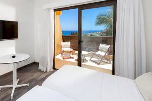 Ein Zimmer im Sol Fuerteventura Jandia Hotel mit Balkon, Fernseher, Tisch und Stühlen.