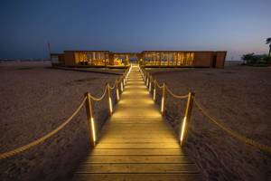 Nachtansicht des Oasis Salinas Sea Hotels am Strand mit beleuchtetem Holzsteg.
