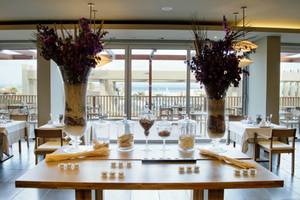 Innenansicht des Restaurants Oasis Salinas Sea mit Tischdekoration und Blick auf das Meer.