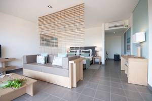 Modernes Hotelzimmer im Oasis Salinas Sea mit Bett, Sofa, Tisch und Klimaanlage.