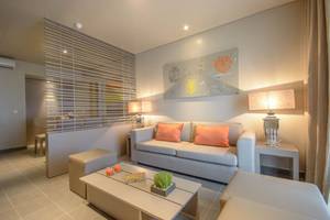 Wohnzimmer im Oasis Salinas Sea Hotel mit grauer Couch, orangen Kissen und modernen Kunstwerken.
