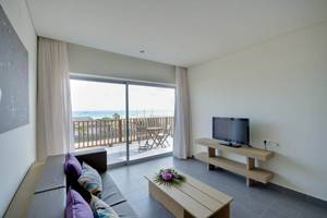 Wohnzimmer mit Meerblick im Oasis Salinas Sea Hotel mit Fernseher und Couch.