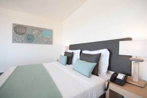 Ein stilvolles Hotelzimmer im Oasis Salinas Sea mit einem Doppelbett, Kissen, Telefon und Lampe.