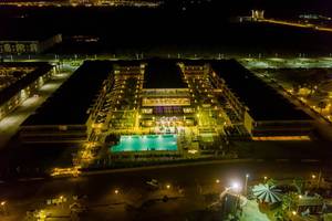 Abendansicht des Oasis Salinas Sea Hotels mit beleuchtetem Swimmingpool und Gebäuden.