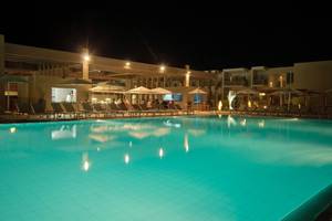 Pool des Oasis Salinas Sea Hotels bei Nacht mit beleuchteten Sonnenschirmen und Liegestühlen.