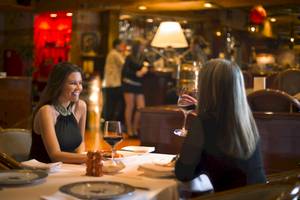 Zwei Frauen im Restaurant Al Ain Rotana mit Weinglas unterhalten sich.