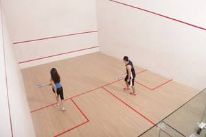 Zwei Leute spielen Squash in einem Innenraum mit roten Linien auf dem Boden.