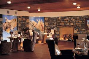 Innenbereich des Elounda Beach Hotel & Villas mit Steinwänden, Tischen und Stühlen.