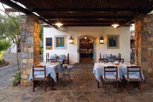 Außenbereich des Elounda Beach Hotel & Villas mit blau-weiß karierten Tischdecken und Steinsäulen.