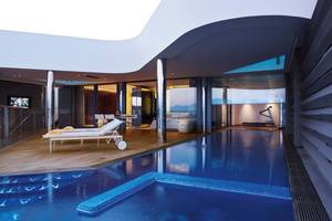 Innenpool des Elounda Beach Hotel mit Loungebereich und Fitnessgeräten.