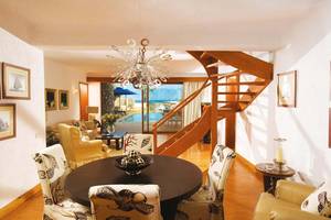 Wohnzimmer im Elounda Beach Hotel & Villas mit Esstisch, Sofas und Blick auf einen Pool.