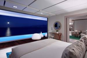 Schlafzimmer im Elounda Beach Hotel & Villas mit Meerblick und beleuchtetem Pool.