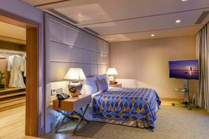 Schlafzimmer im Elounda Beach Hotel & Villas mit Bett, Nachttischen, Lampen und Fernseher.