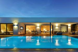 Nachtansicht des Pools des Elounda Beach Hotel & Villas mit beleuchteten Innenräumen