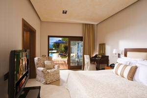 Schlafzimmer im Elounda Beach Hotel & Villas mit Fernseher, Bett und Zugang zur Terrasse