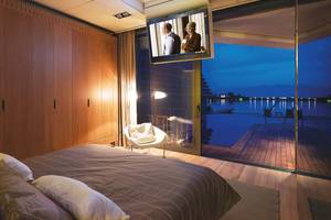 Schlafzimmer im Elounda Beach Hotel mit Aussicht auf den See und eine Terrasse.