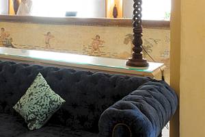 Lobby des Djerba Resorts mit schwarzem Sofa, zwei grünen Kissen und einer Glastheke.