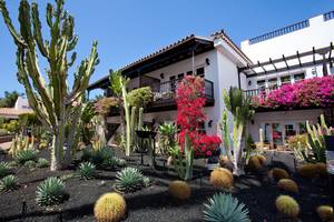 Außenansicht des Seaside Grand Hotel Residencia mit Kakteen und Blumen vor dem Gebäude