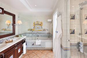 Badezimmer im Seaside Grand Hotel Residencia mit Badewanne, Dusche, Waschbecken und blau-weißen Fliesen.
