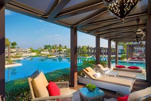 Pool-Loungebereich im W Muscat Hotel mit Loungesesseln und Tisch.