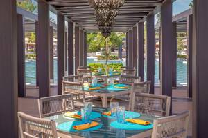 Restaurantterrasse im W Muscat mit Tischen und Stühlen, blauen Tischdecken und Gläsern.