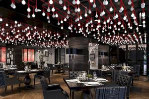 Innenansicht des Restaurants im W Muscat Hotel mit schwarzen Möbeln und roten Lichterketten an der Decke.