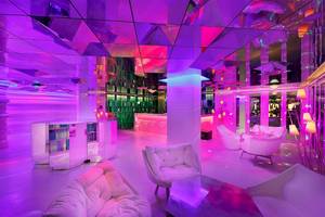 Innenbereich des W Muscat Hotels mit pinken und violetten Lichtern und modernen Möbeln.