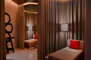 Loungebereich im W Muscat Hotel mit zwei Sesseln, roten Kissen und braunen Vorhängen.