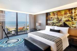 Ein modernes Hotelzimmer im W Muscat mit Meerblick, großem Bett und Balkon.