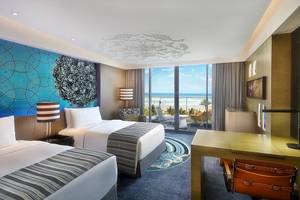 Doppelzimmer im W Muscat Hotel mit Meerblick, modernen Möbeln und blauen Wandmustern.