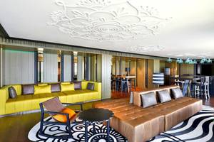 W Muscat Hotel Lobby Innenraum mit gelbem und braunem Sofa und Tisch.