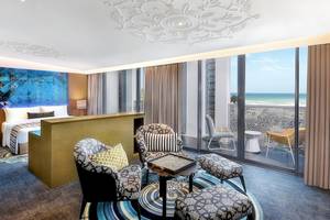 Innenansicht des Hotelzimmers W Muscat mit einem Bett, Wohnzimmerbereich und Blick auf das Meer.