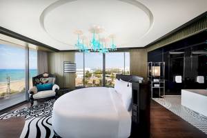 Suite Zimmer im W Muscat mit Blick auf das Meer und eine blaue Kristallkronleuchter.