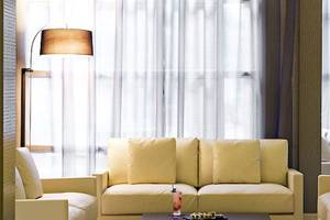 Wohnzimmer im Barcelo Palmeraie Hotel mit beigefarbenen Sofas und weißem Vorhang.
