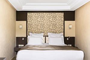 Hotelzimmer im Barcelo Palmeraie mit arabischer Kalligrafie am Kopfende des Bettes.